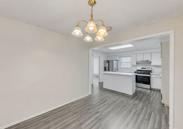 kitchen with light wood finished floors, an inviting chandelier, stainless steel appliances, white cabinetry, and light countertops