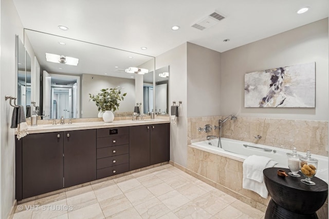 full bath with double vanity, a sink, a bath, and recessed lighting