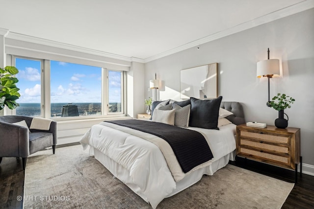 bedroom featuring ornamental molding, a water view, baseboards, and wood finished floors