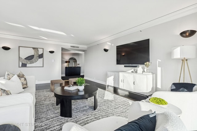 living room with ornamental molding, visible vents, baseboards, and wood finished floors