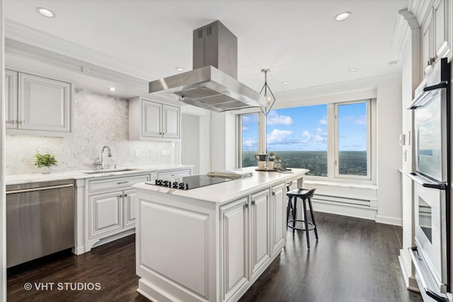 kitchen featuring island range hood, a kitchen island, appliances with stainless steel finishes, hanging light fixtures, and light countertops