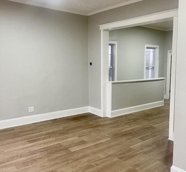 empty room featuring baseboards, wood finished floors, and ornamental molding