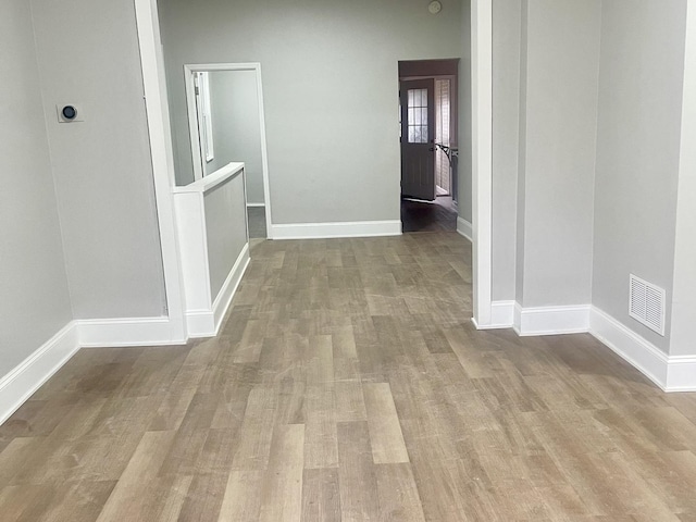 corridor with baseboards, visible vents, and wood finished floors