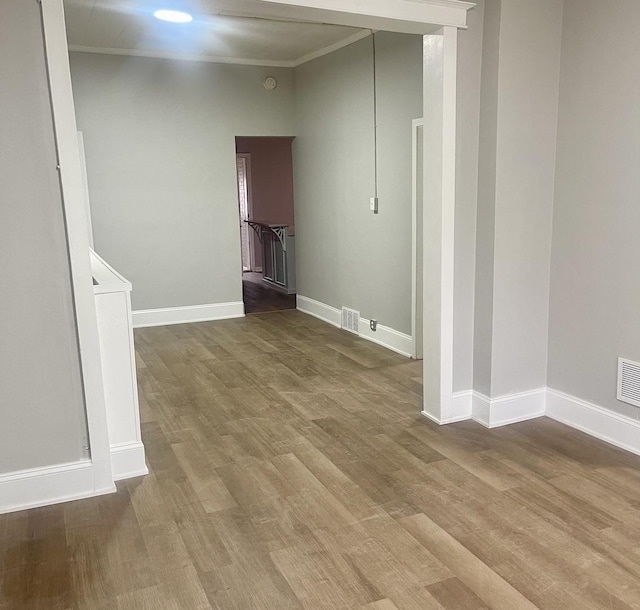 spare room featuring visible vents, crown molding, baseboards, and wood finished floors