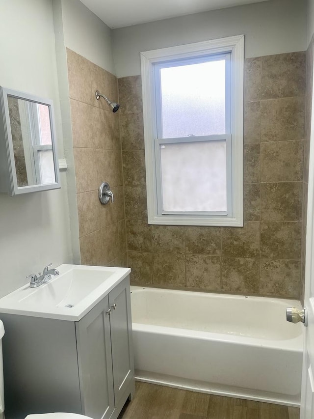 bathroom with washtub / shower combination, wood finished floors, and vanity