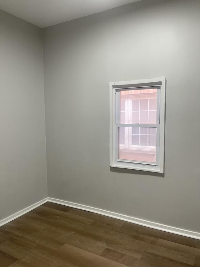 unfurnished room featuring dark wood-type flooring and baseboards