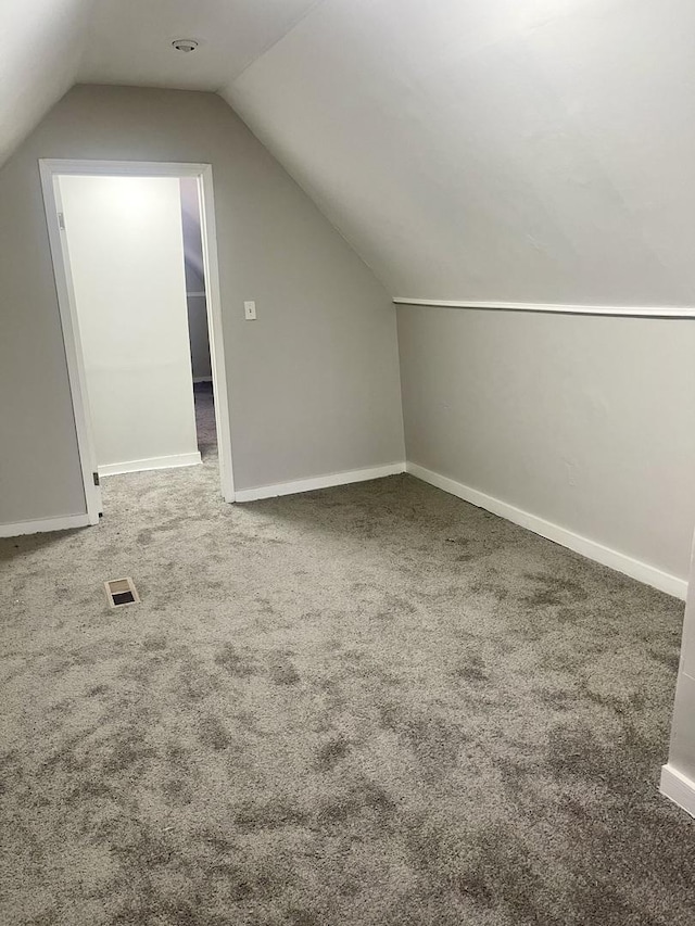 bonus room with carpet floors, baseboards, visible vents, and vaulted ceiling