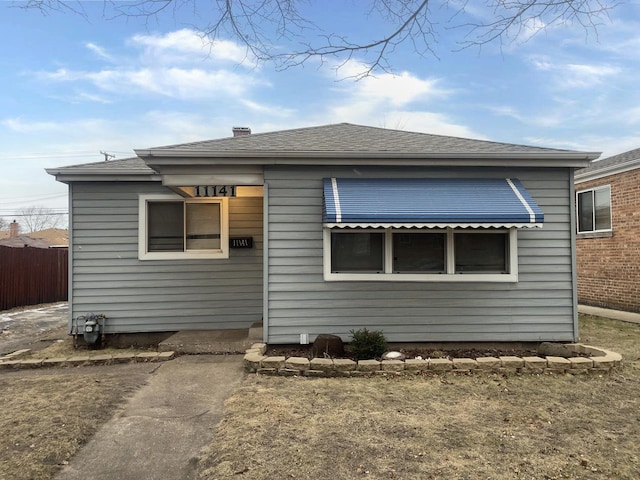 rear view of property with roof with shingles and fence