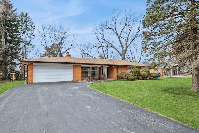 single story home featuring brick siding, a chimney, a front yard, a garage, and driveway