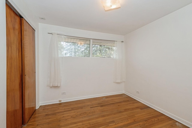 spare room with baseboards and wood finished floors