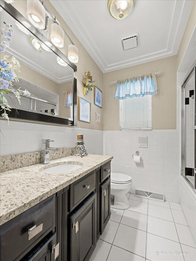 full bath with toilet, vanity, tile walls, and tile patterned floors