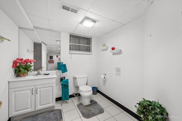 bathroom featuring a drop ceiling, tile patterned flooring, toilet, vanity, and visible vents