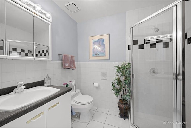 bathroom featuring visible vents, toilet, tile patterned flooring, vanity, and tile walls