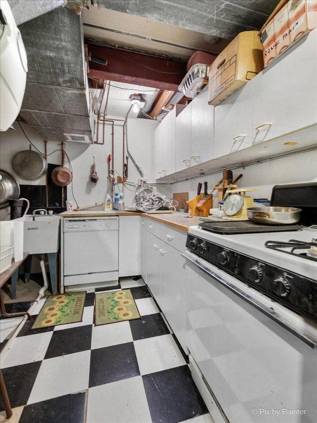 kitchen with dark floors, white appliances, and white cabinetry