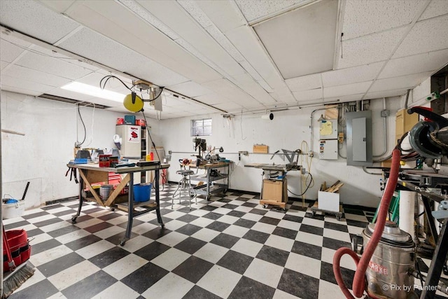 basement featuring dark floors, a drop ceiling, and electric panel