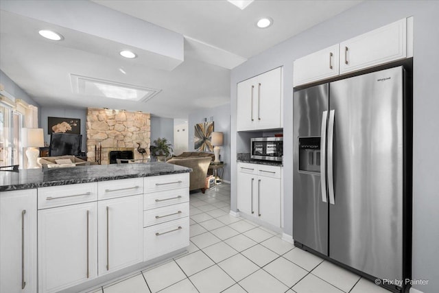 kitchen with light tile patterned floors, white cabinets, open floor plan, appliances with stainless steel finishes, and dark stone countertops