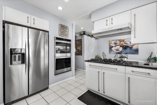 kitchen featuring white cabinets, under cabinet range hood, stainless steel appliances, and dark stone countertops