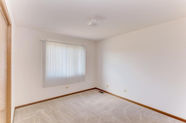 carpeted spare room featuring visible vents and baseboards