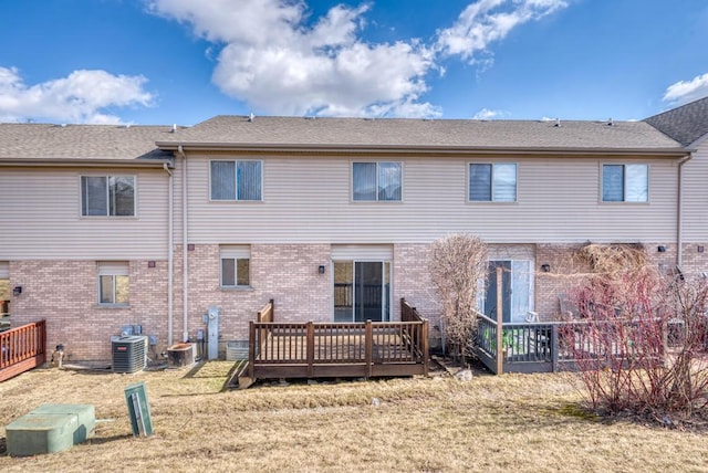 rear view of property featuring brick siding, central AC unit, a yard, and a deck