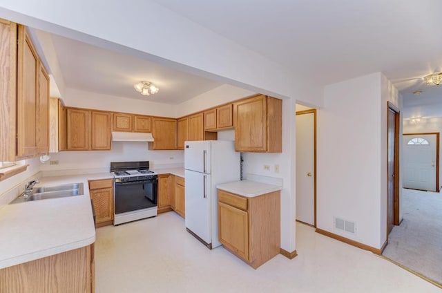 kitchen with visible vents, under cabinet range hood, gas range oven, freestanding refrigerator, and a sink