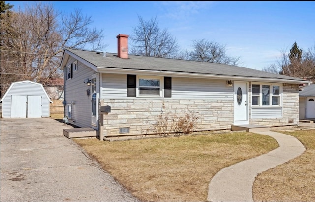 view of front of house featuring an outbuilding, a storage unit, stone siding, and a chimney