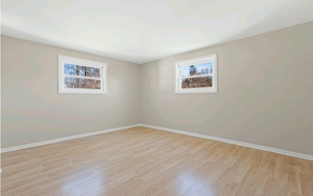 spare room featuring baseboards and light wood-style flooring