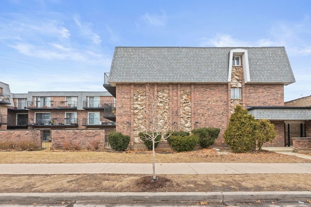 view of side of home with brick siding and roof with shingles