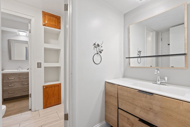 bathroom with wood finish floors, toilet, and vanity