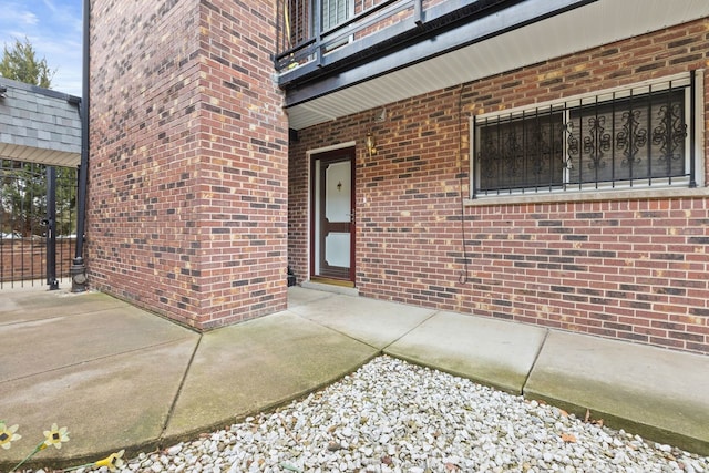 view of exterior entry featuring a patio area and brick siding