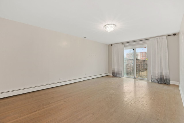 empty room with visible vents, wood finished floors, baseboards, and a baseboard radiator