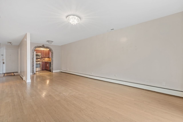 unfurnished living room featuring light wood-type flooring, visible vents, arched walkways, a baseboard radiator, and baseboard heating