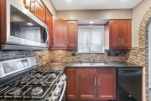 kitchen featuring a sink, stainless steel appliances, tasteful backsplash, and dark countertops