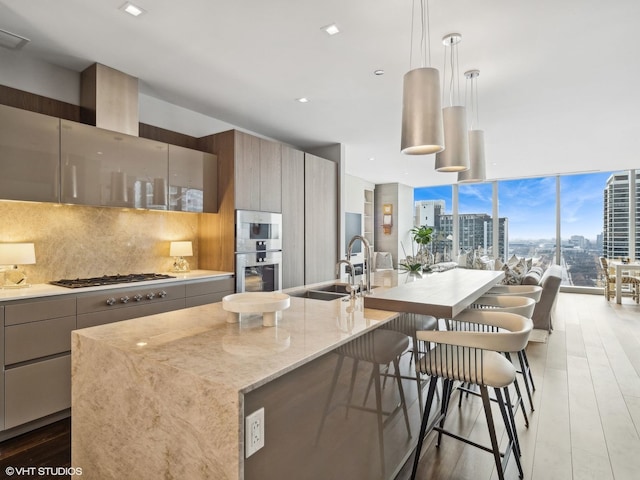 kitchen with backsplash, a city view, expansive windows, gas stovetop, and a sink