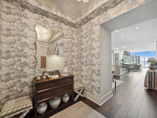 corridor with wallpapered walls, wood finished floors, and baseboards