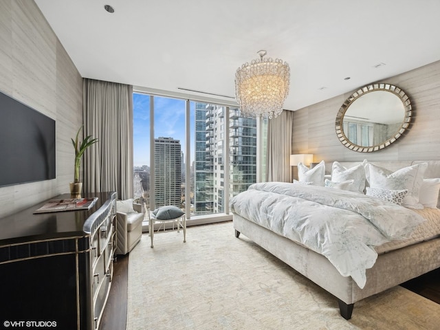 bedroom featuring a city view, a wall of windows, and an inviting chandelier