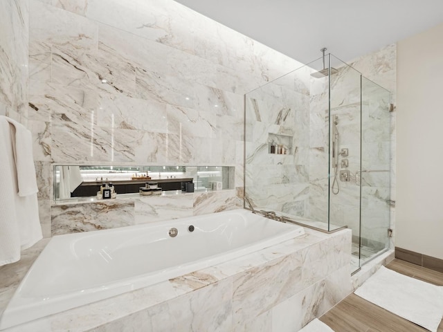 full bathroom with a bath, wood finished floors, baseboards, and a marble finish shower