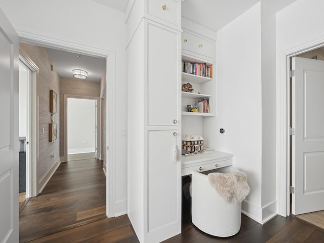 corridor featuring baseboards and dark wood finished floors