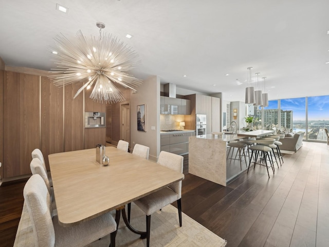 dining area with floor to ceiling windows, wood walls, recessed lighting, dark wood-style floors, and a notable chandelier