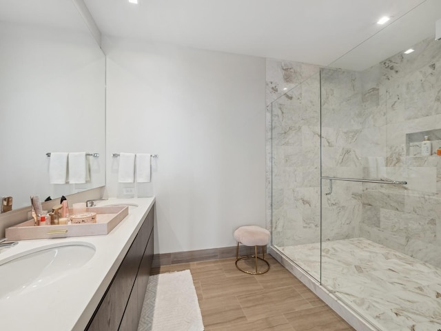 bathroom with a sink, a marble finish shower, baseboards, and double vanity