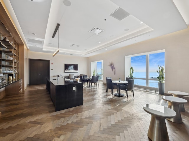 interior space featuring a tray ceiling, open floor plan, visible vents, and a kitchen island