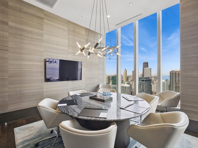 dining area with a notable chandelier, floor to ceiling windows, plenty of natural light, and wood finished floors