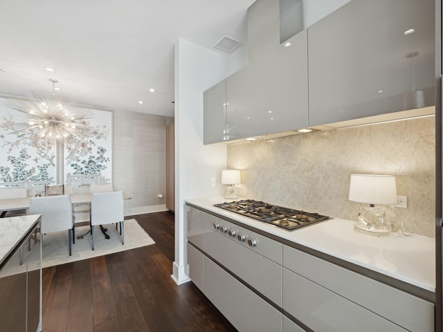 kitchen featuring visible vents, dark wood-type flooring, an inviting chandelier, stainless steel gas stovetop, and light countertops