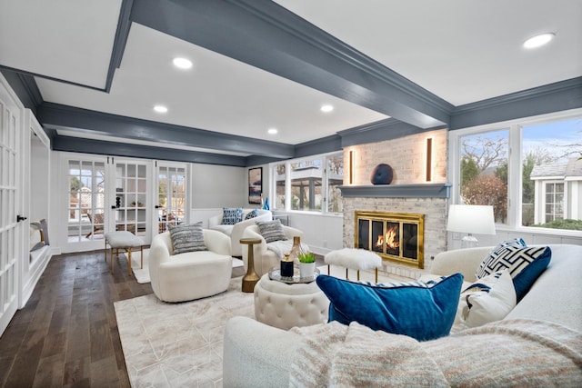 living room featuring ornamental molding, beamed ceiling, and a brick fireplace