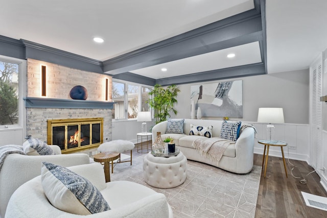 living area featuring ornamental molding, a brick fireplace, wood finished floors, and visible vents