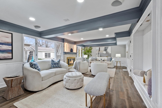 living room featuring a wainscoted wall, crown molding, a fireplace, and wood finished floors