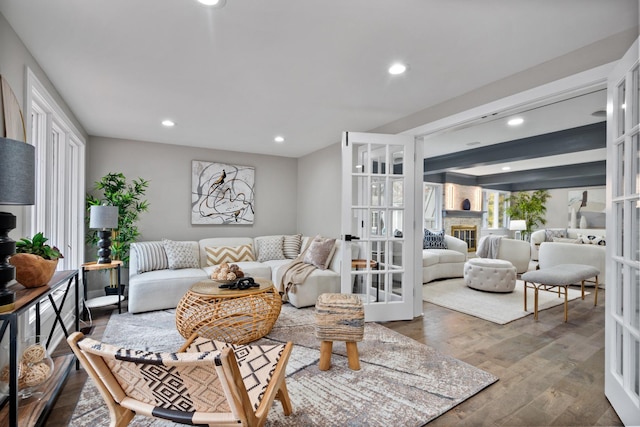 living room with beam ceiling, french doors, recessed lighting, a glass covered fireplace, and wood finished floors