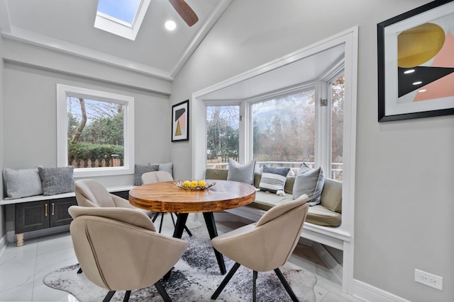 dining room featuring marble finish floor, vaulted ceiling with skylight, a ceiling fan, and baseboards