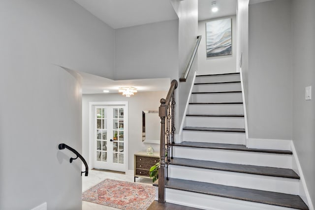 stairs with french doors, a towering ceiling, and baseboards