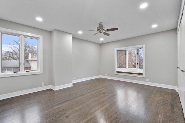 empty room with dark wood-type flooring, recessed lighting, a wealth of natural light, and baseboards