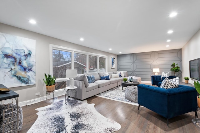 living room with an accent wall, baseboards, dark wood-style flooring, and recessed lighting